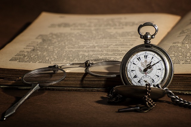 Imagen de un reloj, gafas y libro antiguos.