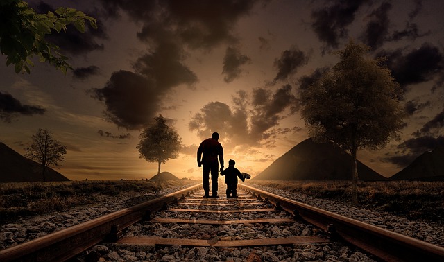 Un padre y su hijo caminando por una vía del tren. Vista de espaldas.